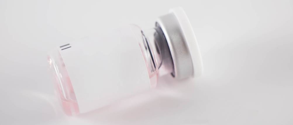 une petite boite en verre presque vide contient encore un produit liquide rose pâle