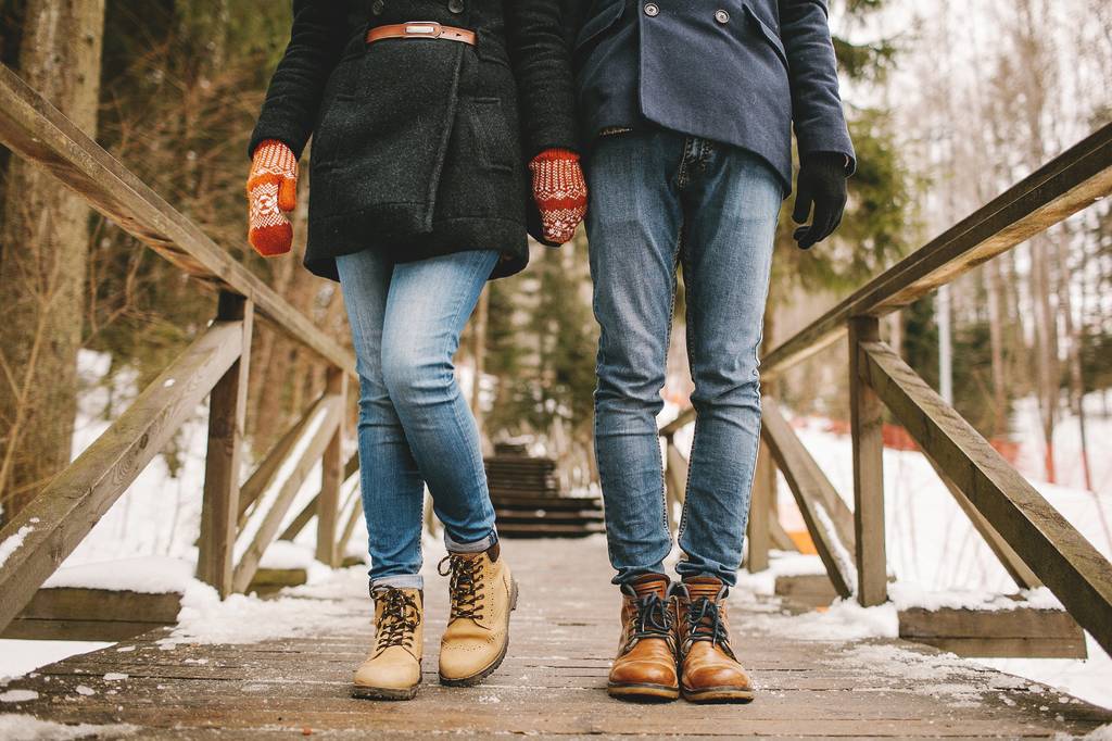 Couple main dans la main debout dans une forêt, équipé de bottes d'hiver