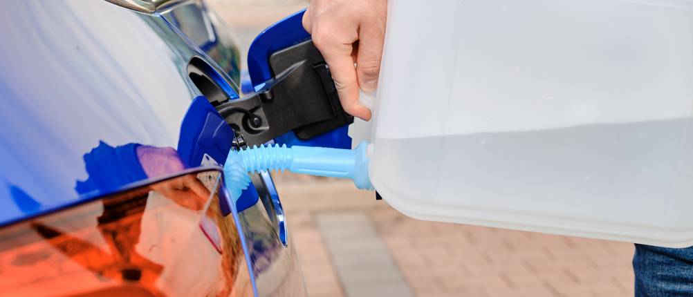 Une personne ajoute de l'additif diesel dans sa voiture bleue