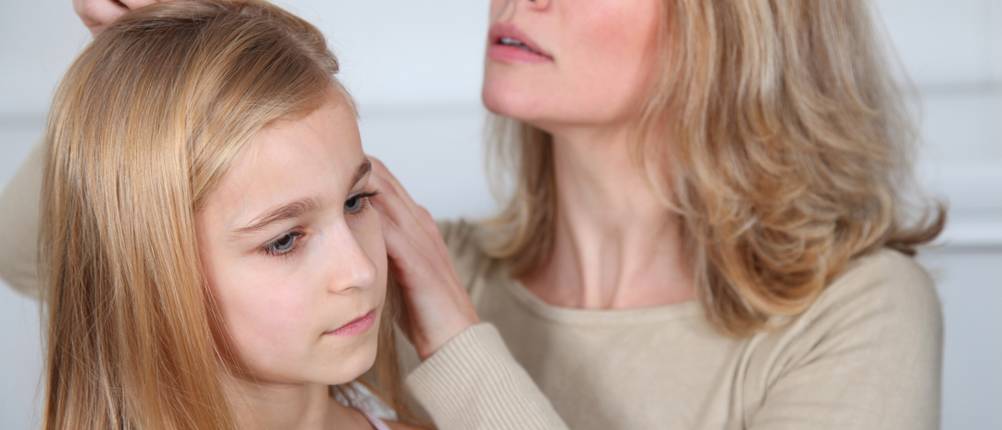 Une mère passe un peigne anti-poux dans les cheveux de sa fille