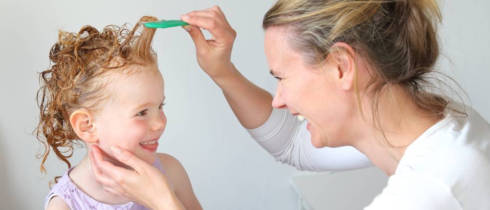 Une maman donne un shampoing anti-poux à son enfant