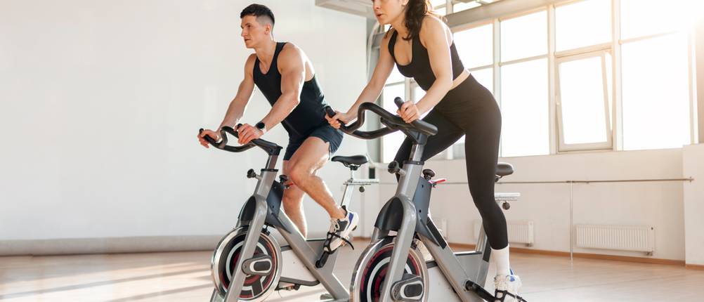 un couple athlétique de cyclistes s'entraîne sur un vélo d'appartement